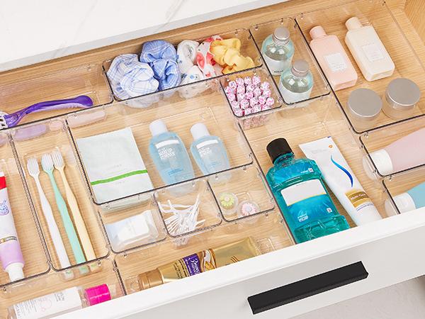 Stackable clear containers holding travel toiletries and spare bathroom supplies