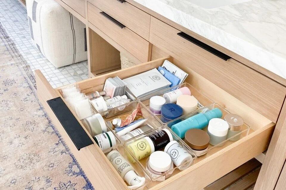 Skincare bottles serums and moisturizers arranged neatly inside a bathroom drawer