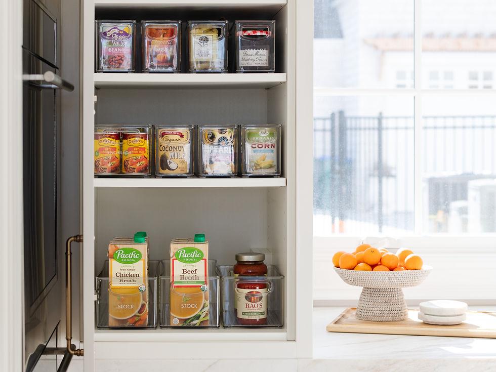 Clear pantry storage bins keep canned vegetables, beans, and soups neatly grouped on shelves.