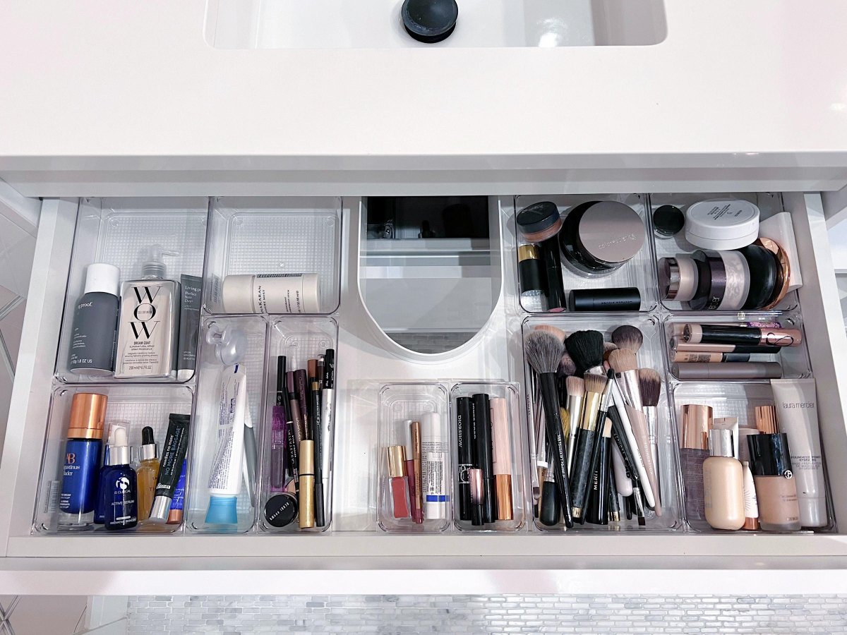 Clear acrylic bathroom drawer trays neatly organizing lipstick foundation and makeup brushes