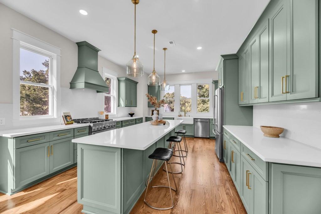 Sage green kitchen cabinets with brass hardware and quartz countertops